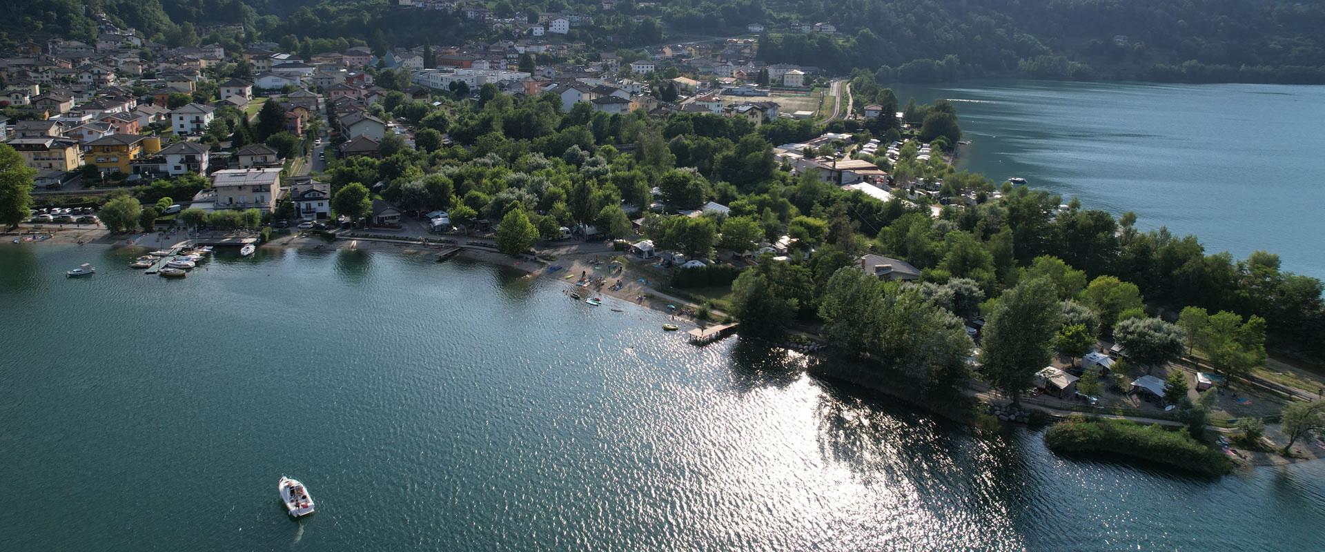 Vista aerea di un lago con case, alberi e una barca in acqua.