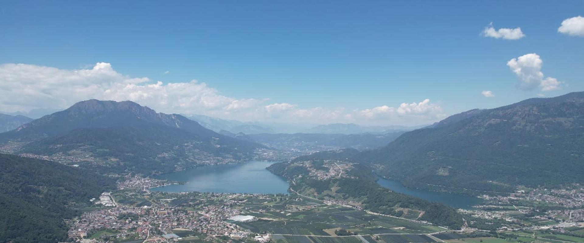 Vista panoramica di un lago circondato da montagne e paesaggi verdi.