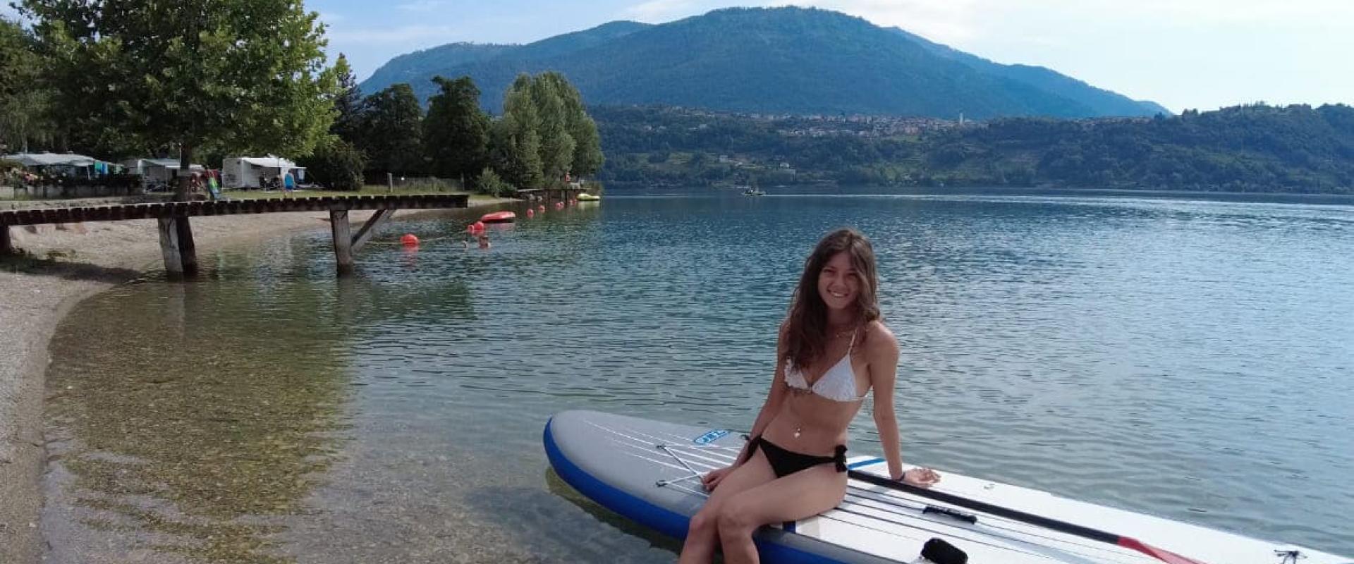 Ragazza in bikini su paddleboard al lago, con montagne sullo sfondo.