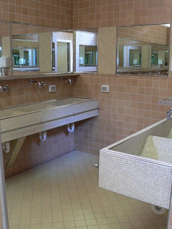 Bagno con lavandini angolari, piastrelle marroni e specchi multipli riflettenti.