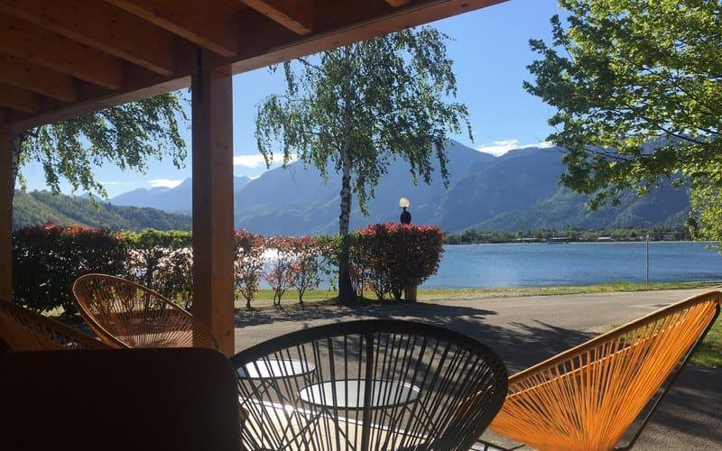 Vista sul lago con montagne, sedie colorate e cielo sereno. Atmosfera rilassante.