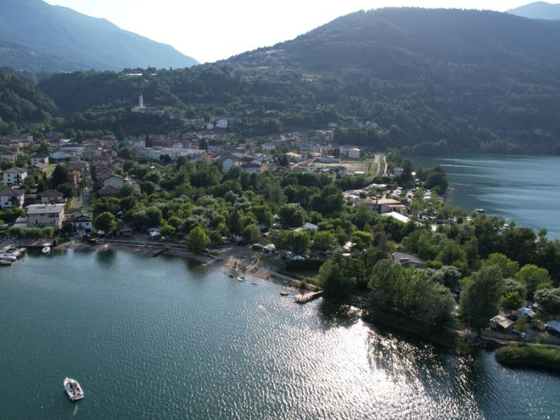 Veduta aerea di un lago con cittadina circondata da colline verdi.