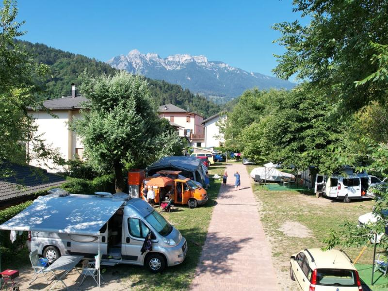 Campeggio in montagna con camper, tende e vista panoramica sulle vette.