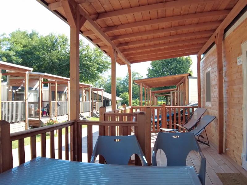 Verande in legno di bungalow con sedie e tavoli all'aperto, immersi nel verde.