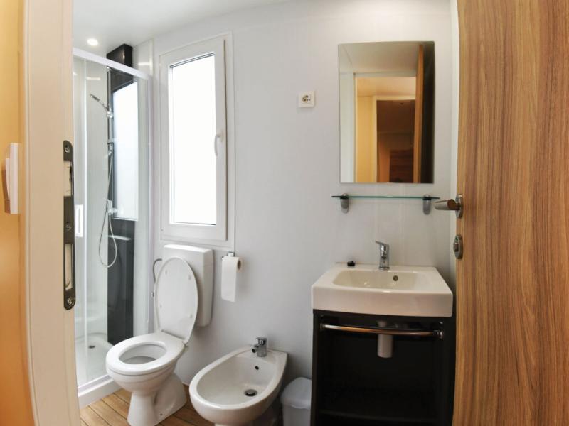 Bagno moderno con doccia, lavabo, WC e bidet, pavimento in legno chiaro.