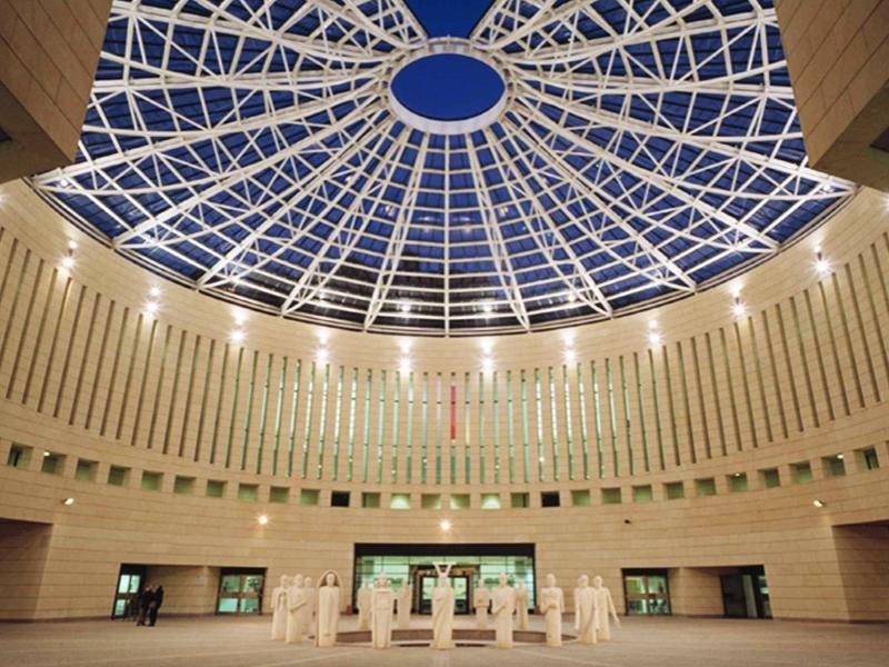 Cupola moderna in vetro e sculture in un ampio spazio interno.