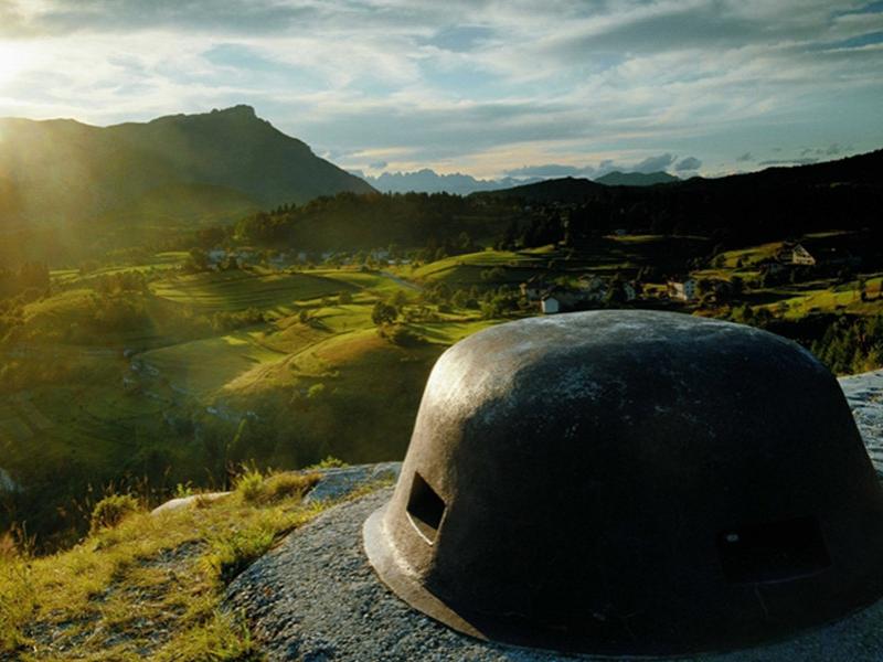 Paesaggio montano con bunker militare al tramonto, vista panoramica sulla valle.